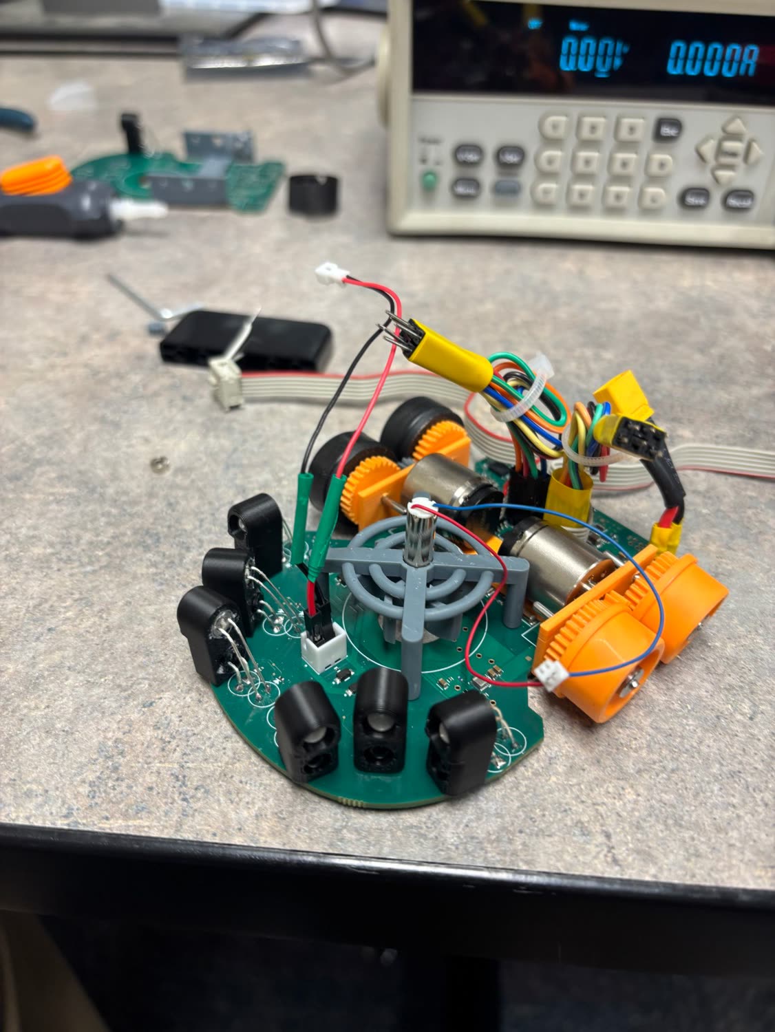 The assembled micromouse on a lab bench, with orange printed drive modules and black wall sensors